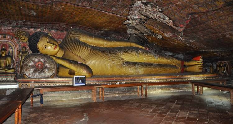 Eine liegende Buddha-Statue in einer kunstvoll verzierten Höhle.