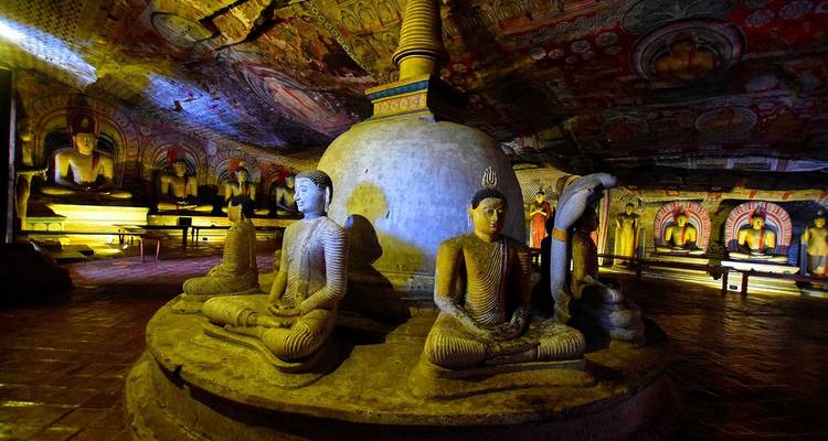 Inneres einer Höhle mit geschnitzten Statuen und einem Stupa.