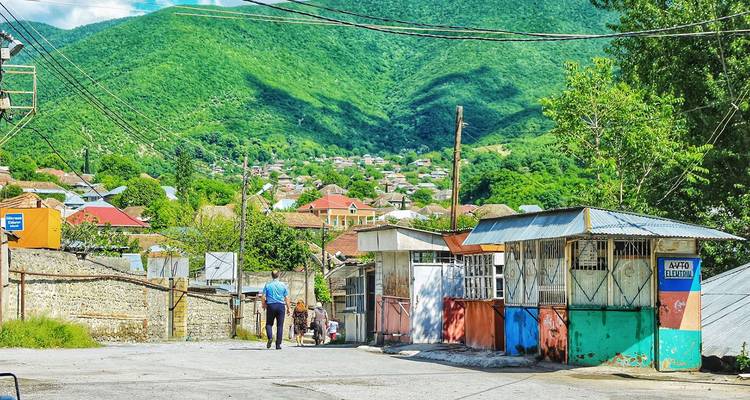 Des gens dans un petit village situé sur fond de montagnes verdoyantes.