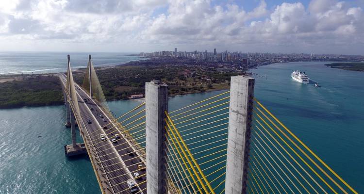 Vue aérienne d'un grand pont avec paysage urbain et littoral.