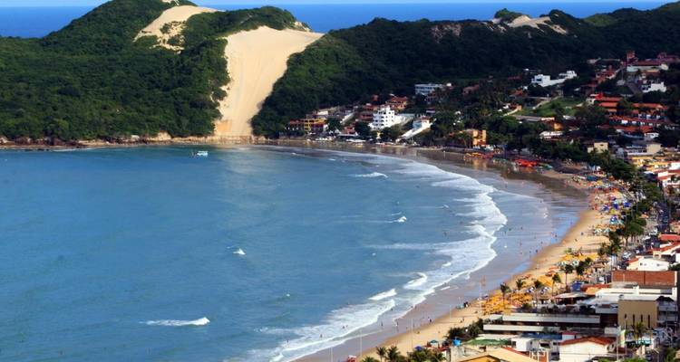 Ville en bord de mer avec une grande dune de sable et des vagues océaniques.
