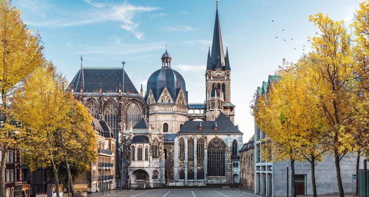 Aachener Dom Außenansicht mit Bäumen in Herbstlaub.