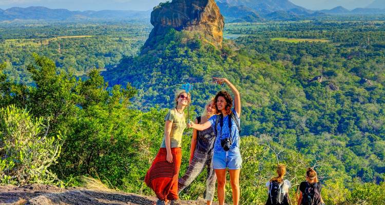 Des touristes prenant la pose près du célèbre rocher de Sigiriya dans un cadre de forêt luxuriante.