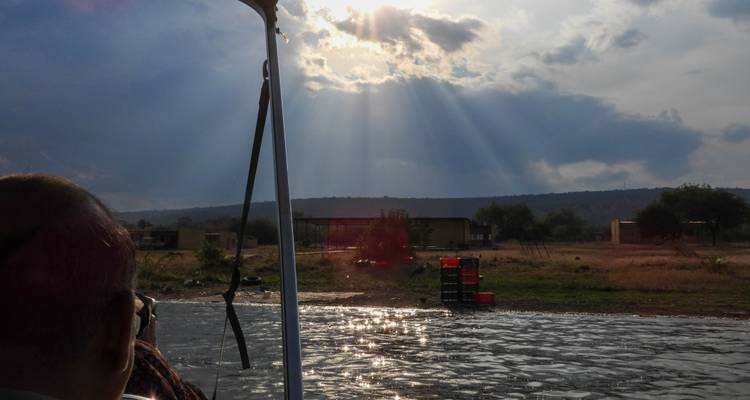 Blick aus einem Fahrzeug, der Sonnenstrahlen zeigt, die durch die Wolken über eine malerische Landschaft scheinen.