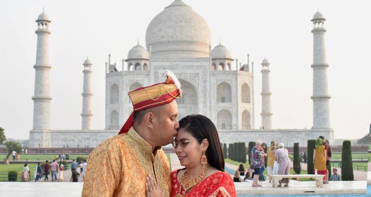 Couple in traditional attire sharing a tender moment with the Taj Mahal in the background.