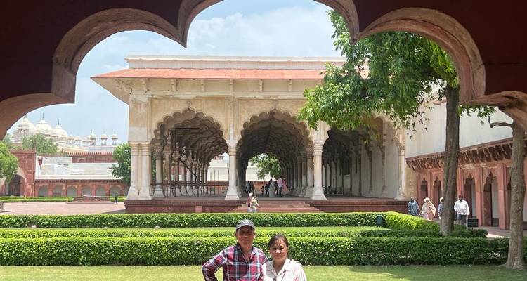 Visitors framed by scalloped arch inside Agra Fort gardens.