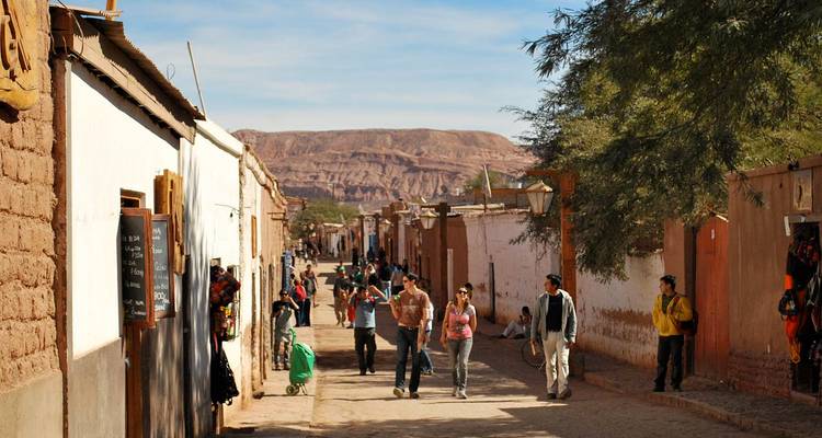 Stoffige adobehoofstraat van San Pedro de Atacama met locals en toeristen die wandelen.
