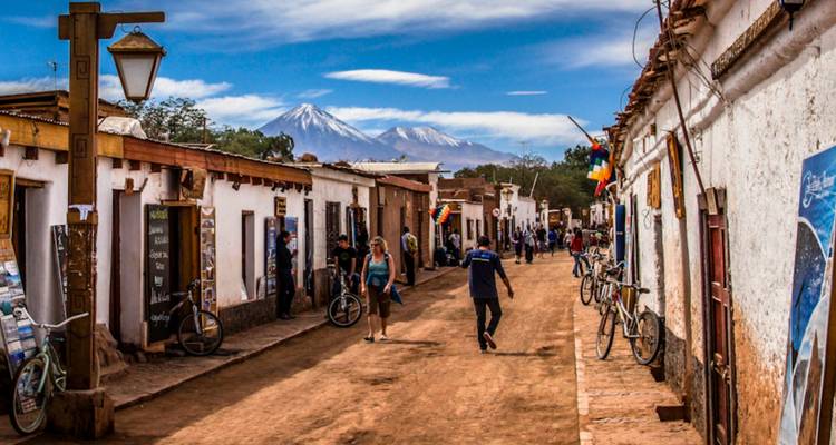 Straatje in het stadje dat leidt naar sneeuwbedekte vulkanen onder een levendige blauwe hemel in de Atacama.