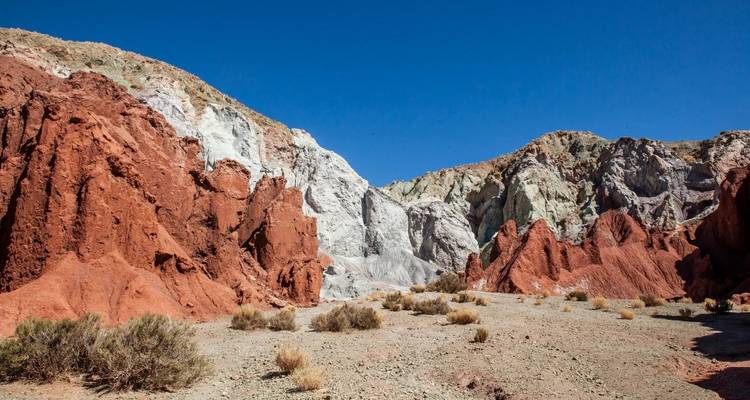 Kleurig gelaagde rode en witte canyonwanden tegen een diepblauwe woestijnhemel.