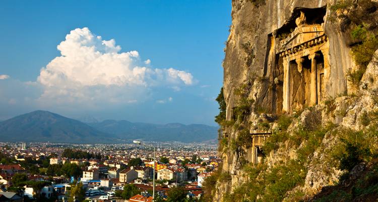 Antiguas tumbas licias excavadas en la roca talladas en un acantilado con vista al valle de Fethiye.