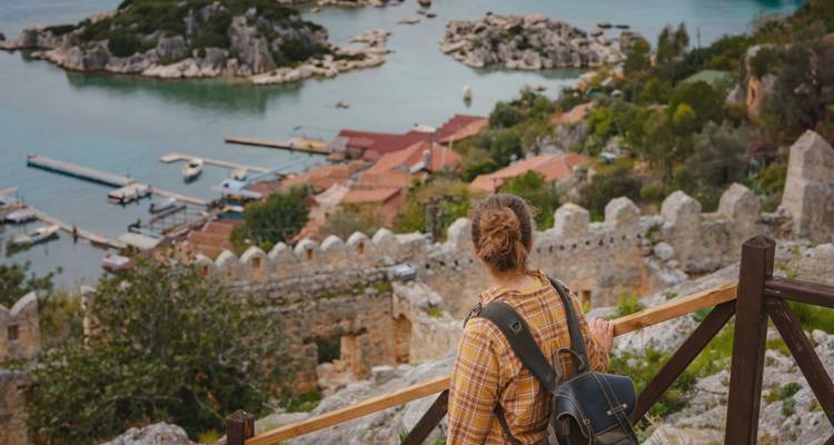 Viajero contemplando las ruinas hundidas de Kekova y las bahías turquesas desde un mirador con barandilla de madera.