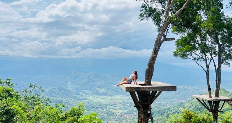 Person entspannt sich auf einer Plattform mit weitem Blick auf die Landschaft.