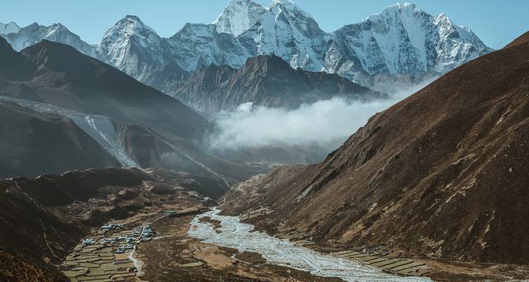 Bergdal met een rivier en besneeuwde toppen.