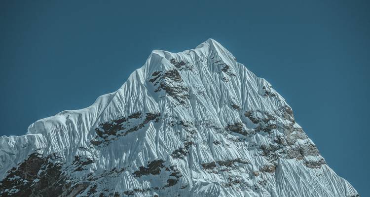 Besneeuwde bergtop tegen een helderblauwe lucht.