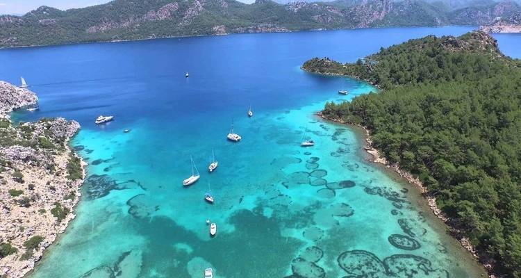 Aerial view of turquoise waters with yachts and rich vegetation.
