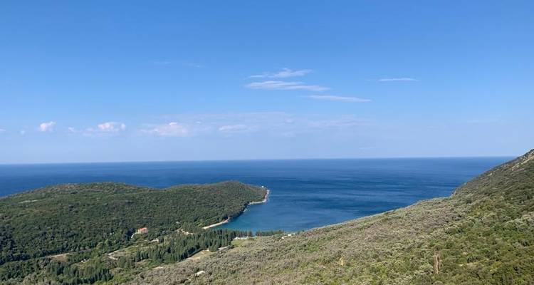 Paysage vallonné rencontrant la mer sous un ciel bleu dégagé.