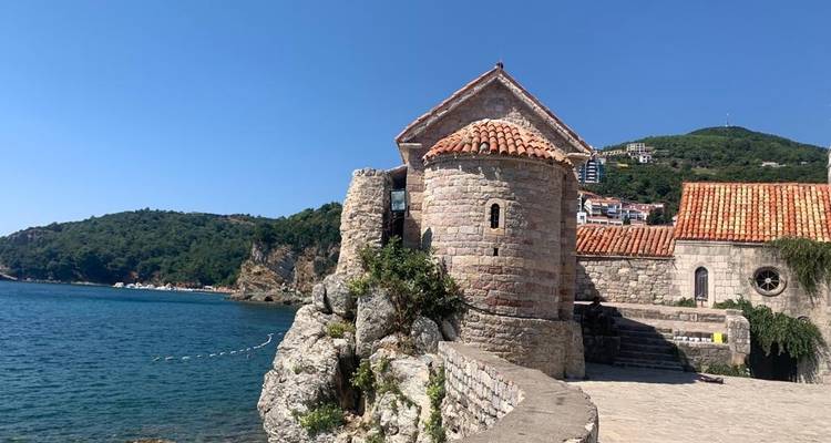 Ancien bâtiment en pierre sur une côte rocheuse avec la mer en vue.