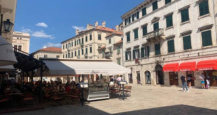 Café en plein air sur une place de style européen avec des gens qui dînent.