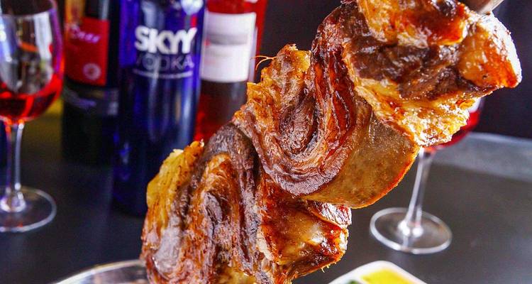 Plan rapproché d'une brochette avec de la viande grillée et des bouteilles en arrière-plan.