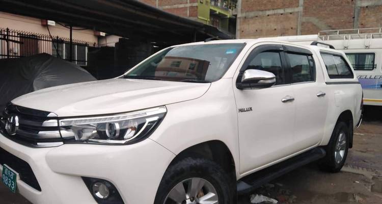 Un véhicule Toyota Hilux blanc stationné dans un environnement urbain.
