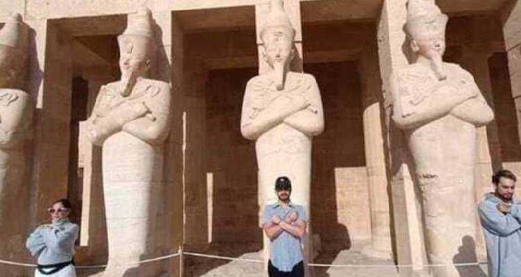 Toeristen die standbeelden nabootsen in een oude tempel.