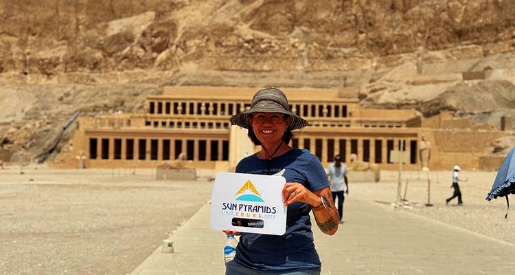 Persoon die een toeristenbord vasthoudt voor de Tempel van Hatshepsut.