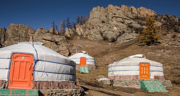 Yourtes traditionnelles aux portes colorées situées dans un paysage rocheux.