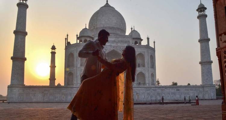 Un couple qui danse devant le Taj Mahal au coucher du soleil.