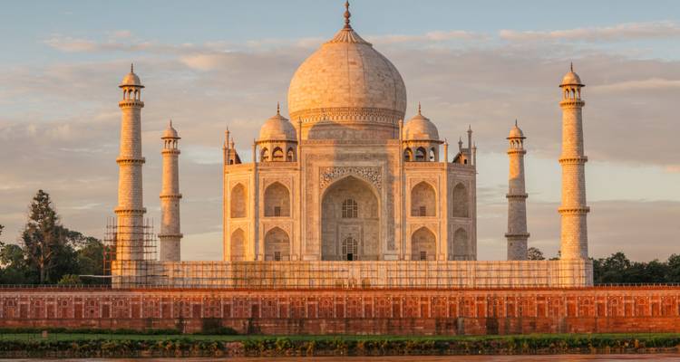 Vista de la hora dorada del Taj Mahal reflejando luz cálida con un cielo tranquilo de fondo