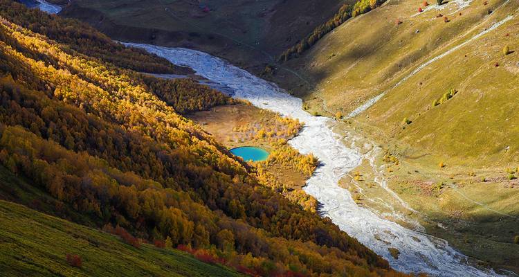 Vue aérienne d'une rivière serpentant à travers une vallée avec un petit lac.