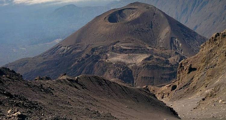 Un cratère volcanique avec un terrain accidenté environnant.