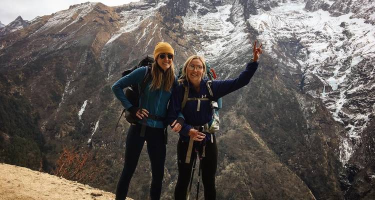 Twee vrouwen poseren voor een foto met een besneeuwde berg op de achtergrond.