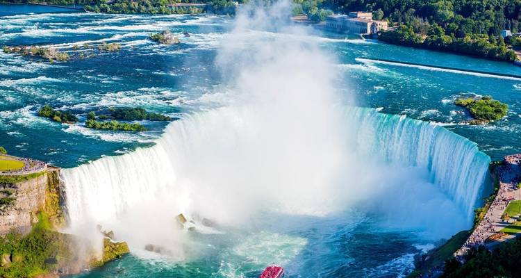 Aerial view of a large waterfall with mist and a boat below