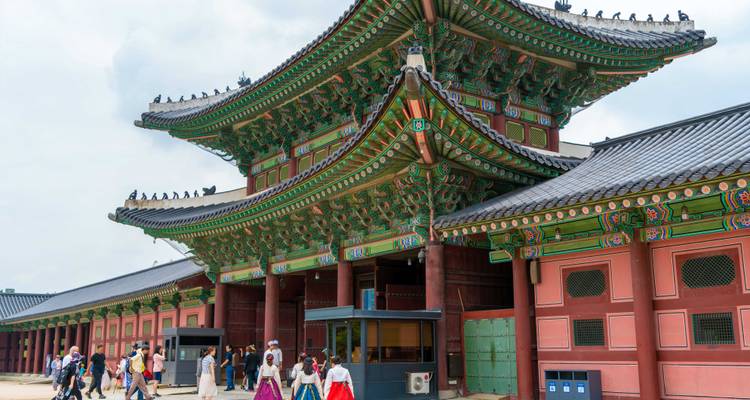 Les visiteurs vêtus de hanbok colorés franchissent la porte principale ornée du Palais de Gyeongbokgung