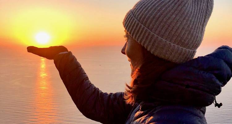 Une personne tenant le soleil dans sa main pendant le coucher de soleil.