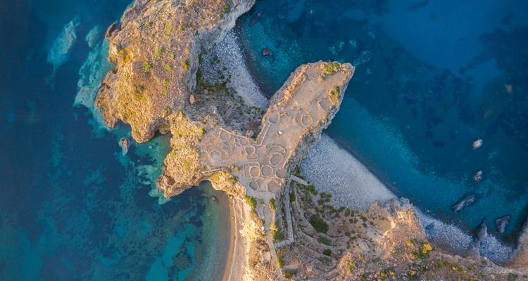 Vue aérienne d'un site archéologique sur une péninsule rocheuse.