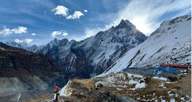 Blick auf den Himalaya mit Trekkern bei einer Berghütte.