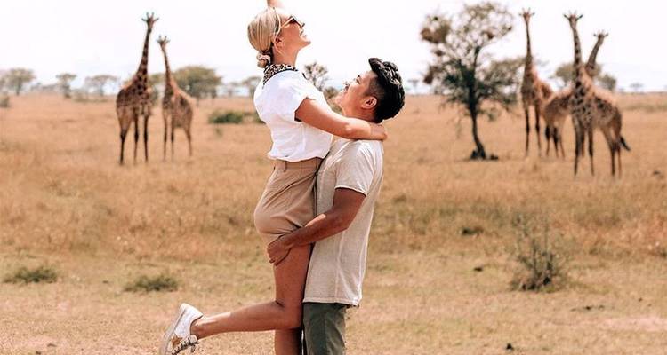 Couple enjoying a safari with giraffes in the background.