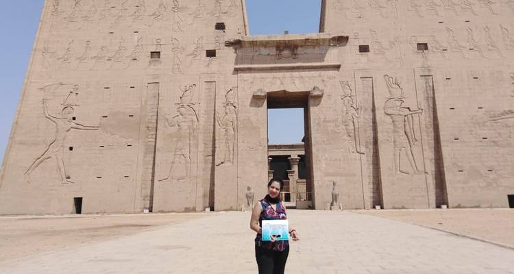 Een vrouw die een toeristenbord vasthoudt bij de Edfu Tempel.