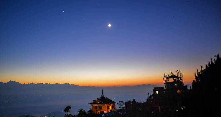 Night view of mountains with a crescent moon in the sky.