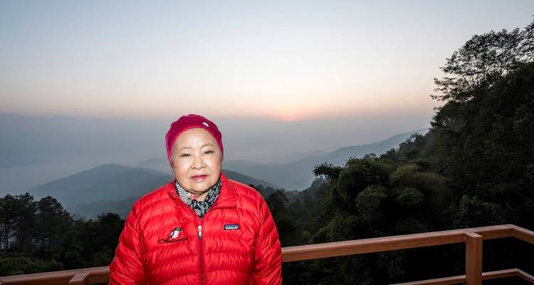 Person in a red jacket with a misty mountain view in the background.