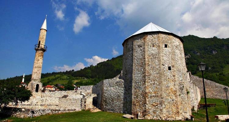 Historisch stenen gebouw met een minaret tegen een blauwe hemel.