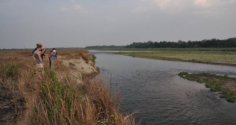 Menschen die langs een rivieroevers landschap lopen.