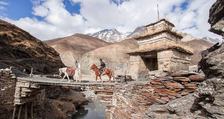 Reiziger te paard die een brug over een rivier oversteekt.