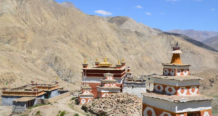 Kleurrijke stupa's in een kaal, rotsachtig landschap.