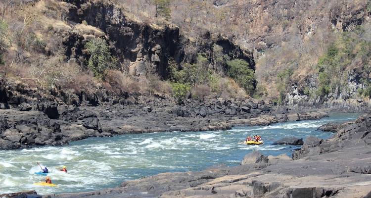 People white water rafting in a rocky river gorge.