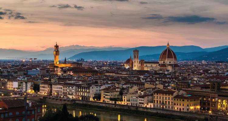 Vue panoramique du coucher de soleil sur Florence avec le Dôme et le Palazzo Vecchio illuminés au-dessus des toits de la ville.