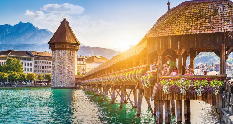 Le pont de la Chapelle, orné de fleurs, enjambant la rivière Reuss à Lucerne sous la lumière dorée du soir.