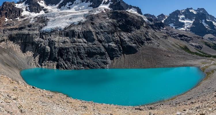 Türkisfarbener Gletschersee umgeben von schroffen Berggipfeln.