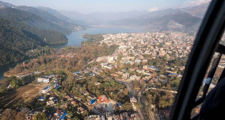 Aerial view of a city with a lake and surrounding hills.